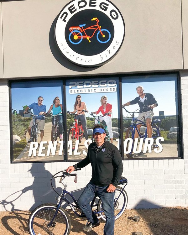 Man standing with bike outside Pedego store.