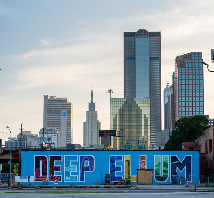 Colorful Deep Ellum sign in front of the Dallas Skyline.