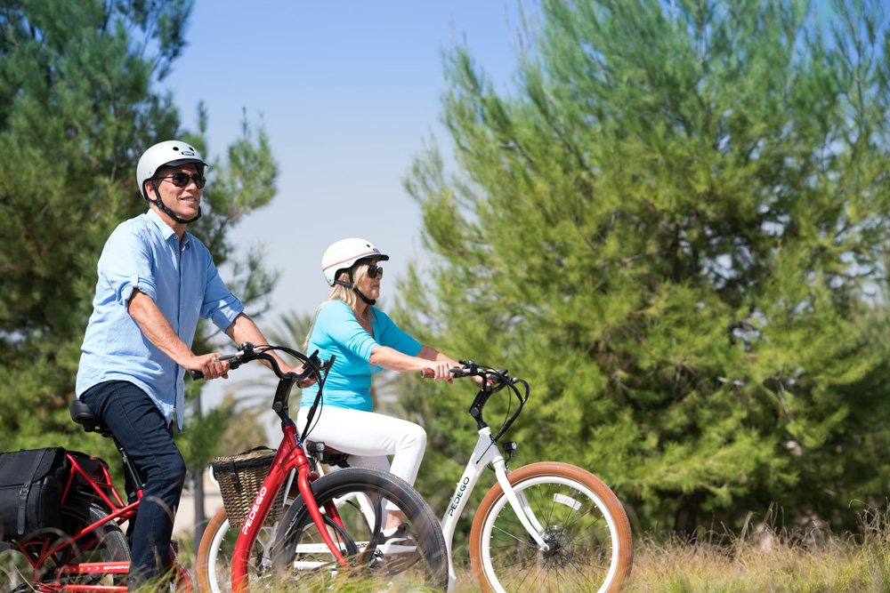 A couple riding their Pedego bikes while wearing Nutcase helmets.