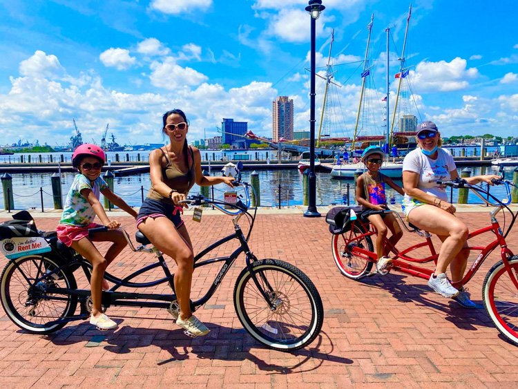 People riding Pedego tandem electric bikes along the waterfront in Norfolk.