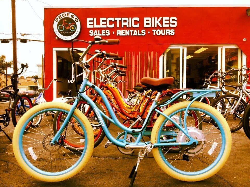 Pedego electric bikes in various colors lined up in front of an e-bike store
